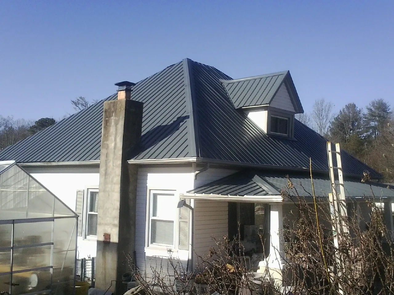 Dark blue standing seam metal roof on a white farmhouse with dormer — Slate & Tile Roof Repair by Roofing Brothers in Olean