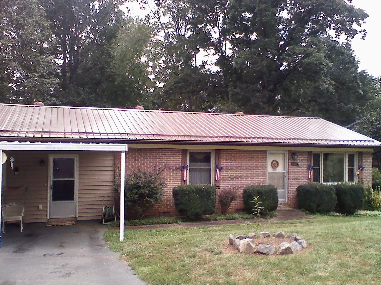 Bronze metal roof and carport on a brick ranch home — Roof Repair work by our crew in Olean